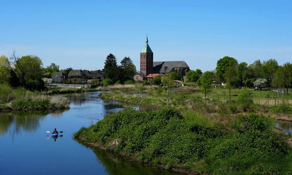 Kanufahrer auf der Niers vor der Pfarrkirche St. Cyriakus in Weeze