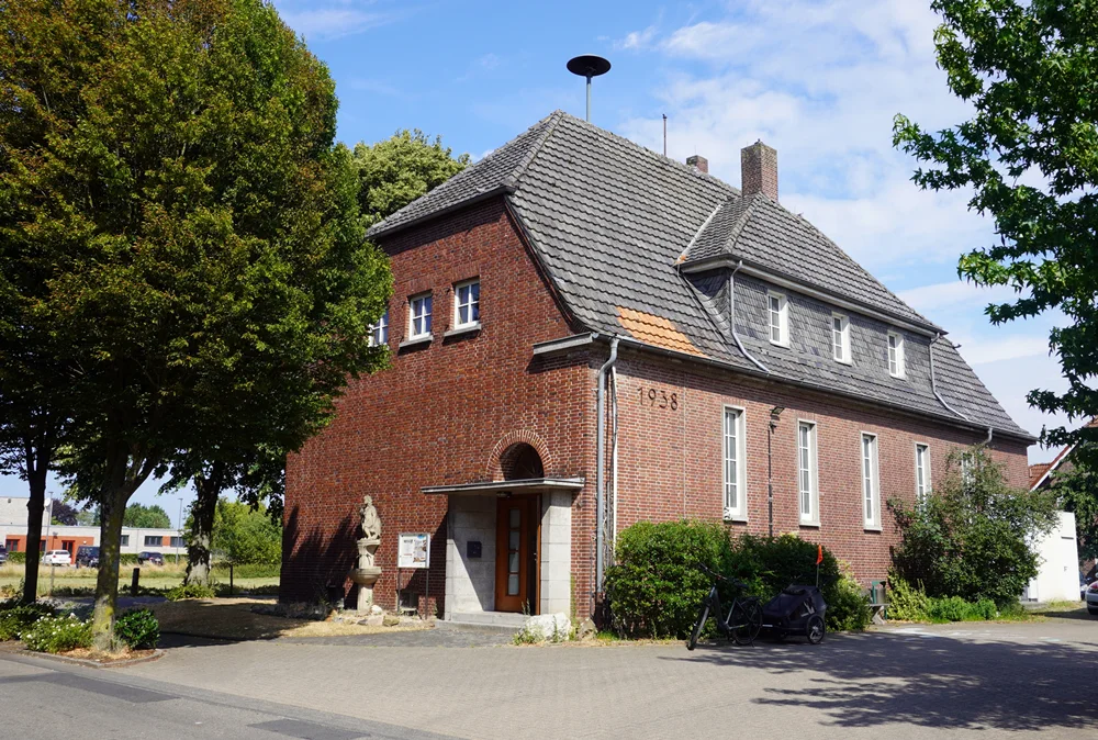 Ehemaliges Schulgebäude der Christophorus-Schule in Wemb. Das historische Backsteingebäude aus dem Jahr 1938 steht zwischen Bäumen und Grünanlagen.