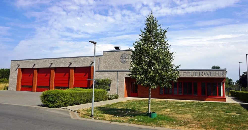 Neubau der Freiwilligen Feuerwehr Wemb aus dem Jahr 2021 mit vier roten Hallentoren und großzügigem Vorplatz.