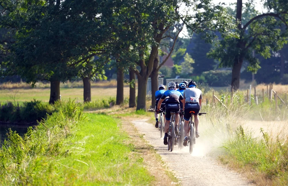 Radfahrer auf dem Nierswanderweg bei Weeze wirbeln beim Vorbeifahren Staub auf.