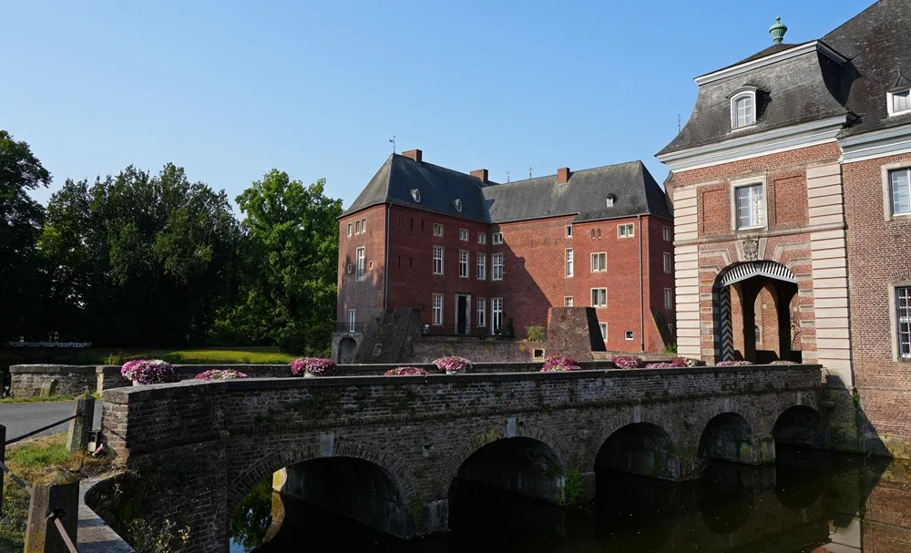 Die Brücke zum Schloss Wissen in Weeze mit dem Eingangstor, dem historischen Backsteinschloss und dem Wassergraben.