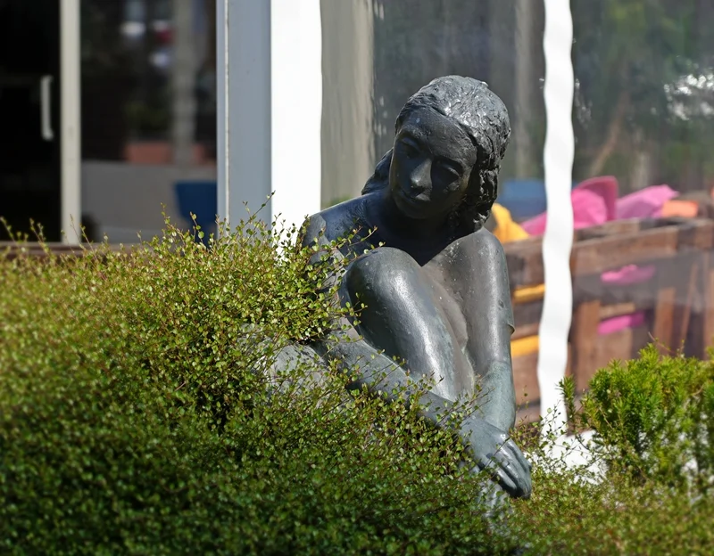Bronzefigur einer sitzenden Frau vor dem Marktcafé in Weeze.