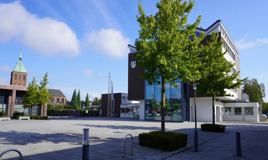 Rathaus Weeze mit moderner Glasfassade und der Kirche St. Cyriakus im Hintergrund