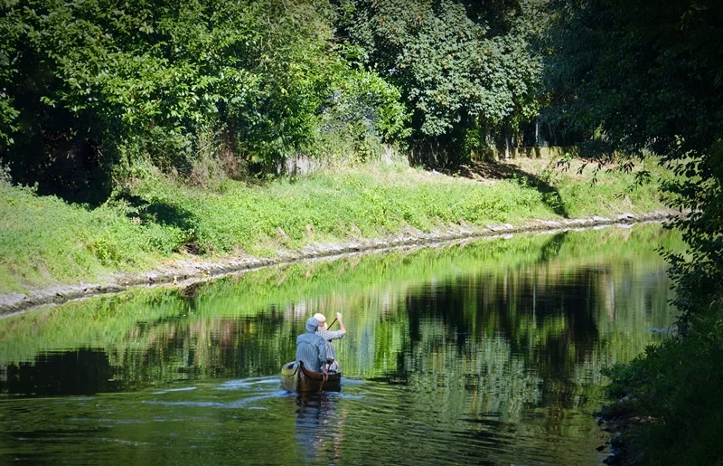 Zwei Paddler auf der Niers am Fährsteg in Weeze, umgeben von dichtem Grün