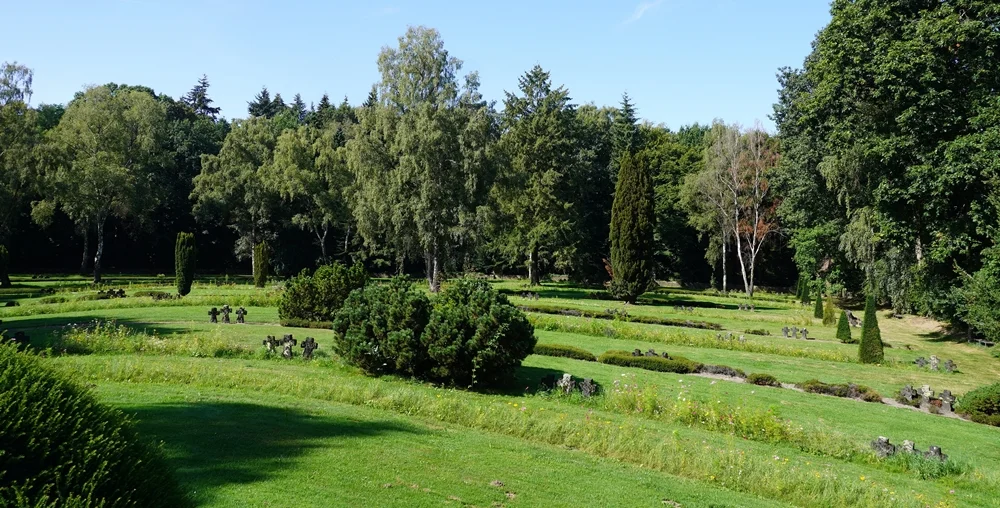 Blick über die grüne und gepflegte Kriegsgräberstätte in Weeze mit Blumen, Bäumen und zahlreichen Grabkreuzen