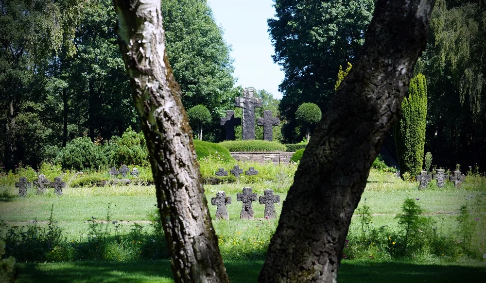 Kriegsgräberstätte in Weeze mit zahlreichen Steinkreuzen, eingerahmt von zwei Baumstämmen