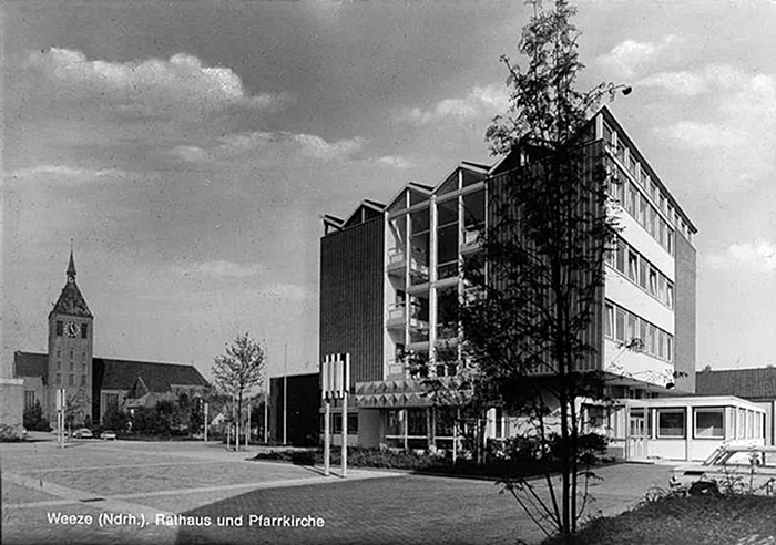 Rathaus Weeze mit moderner Glasfassade und der Kirche St. Cyriakus im Hintergrund