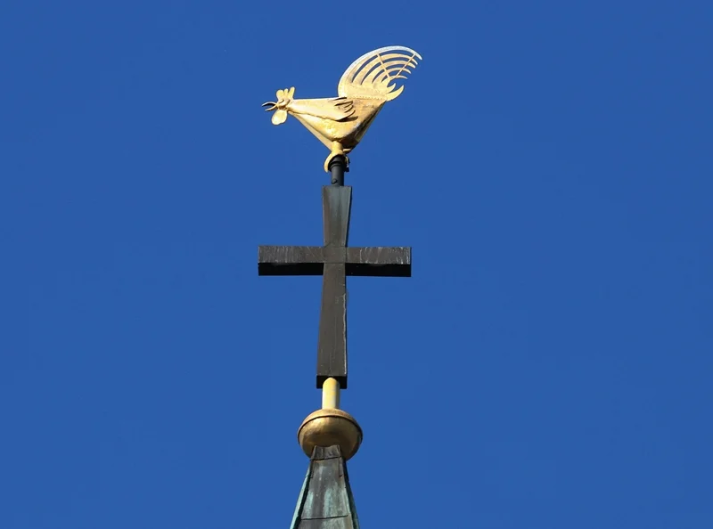 Goldener Wetterhahn auf dem Kreuz der St.-Cyriakus-Kirche in Weeze vor blauem Himmel