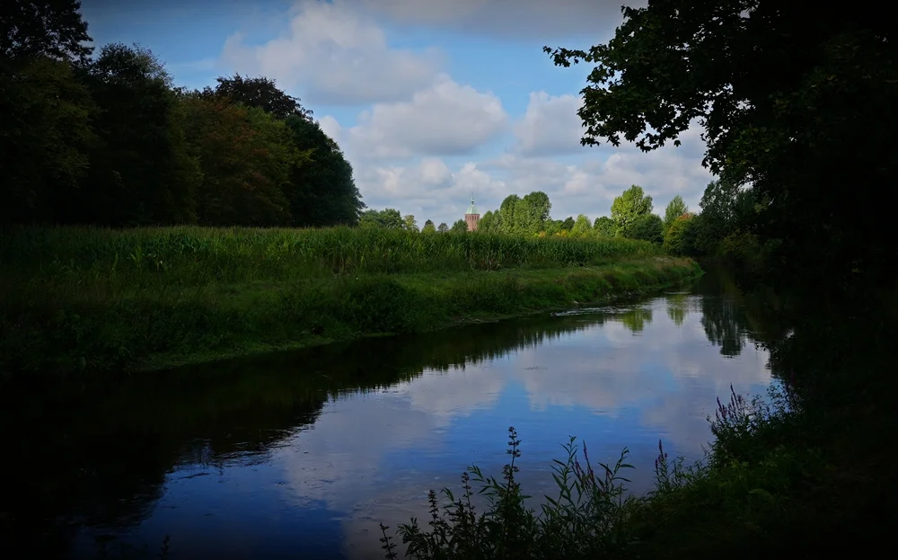 Die Niers bei Weeze mit Wiesen und dem Kirchturm von St. Cyriakus im Hintergrund