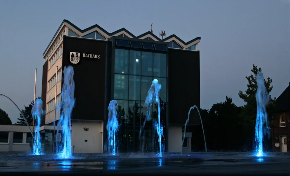 Rathaus in Weeze in der Abenddämmerung mit blau beleuchteten Wasserfontänen