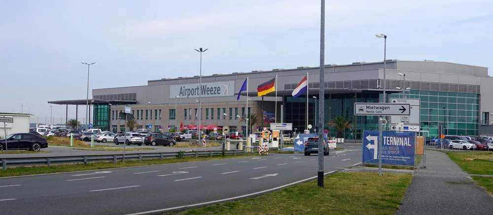 Terminalgebäude des Airport Weeze mit Zufahrt und Fahnen vor dem Haupteingang