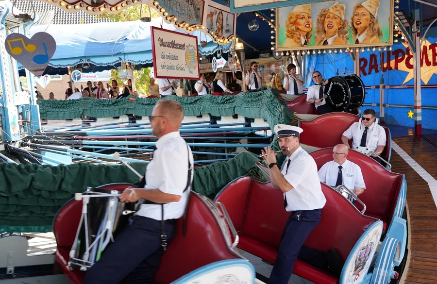 Mitglieder des Tambourcorps Weeze mit ihren Instrumenten in der historischen Raupenbahn auf der Weezer Kirmes