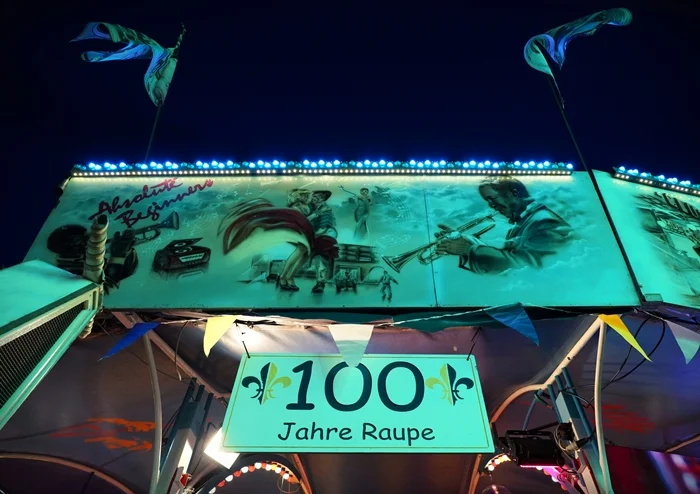 Beleuchtetes Jubiläumsschild „100 Jahre Raupe“ an der historischen Raupenbahn auf der Weezer Kirmes