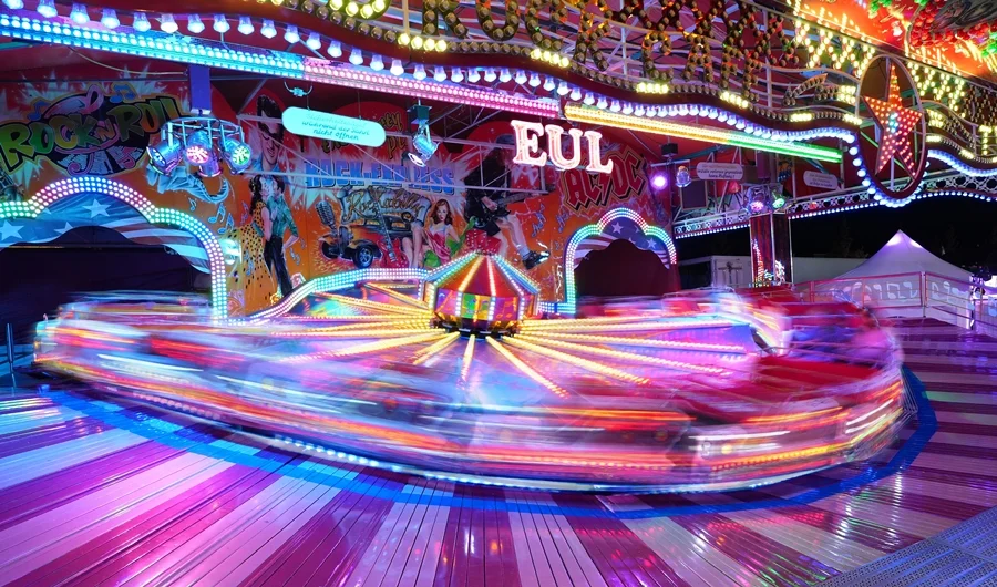 Fahrgeschäft in schneller Bewegung mit bunten Lichtspuren auf der Weezer Kirmes bei Nacht