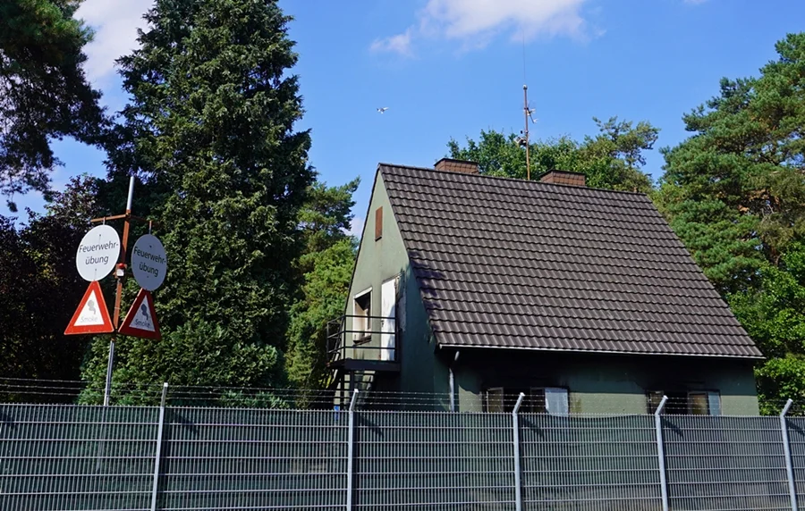 Feuerwehrübungshaus auf Laarbruch mit Übungsschildern und einem Flugzeug am Himmel