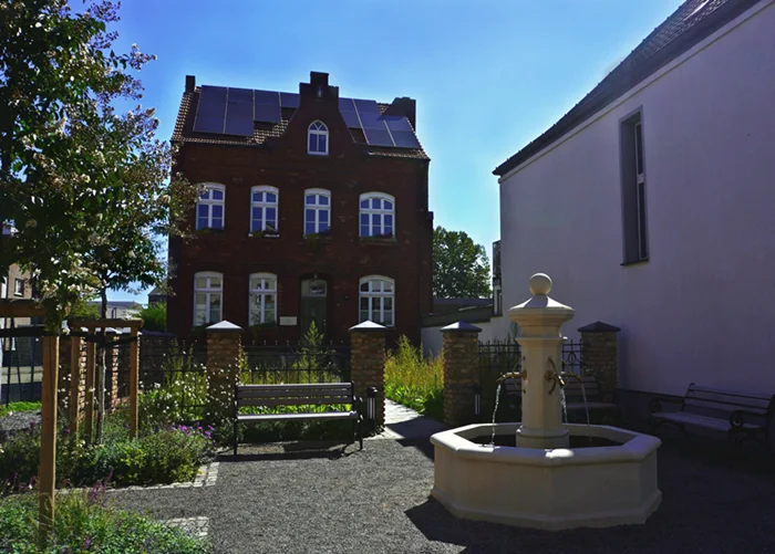Gartenanlage an der Alten Schmiede in Weeze mit Brunnen, Sitzbänken und Bepflanzung