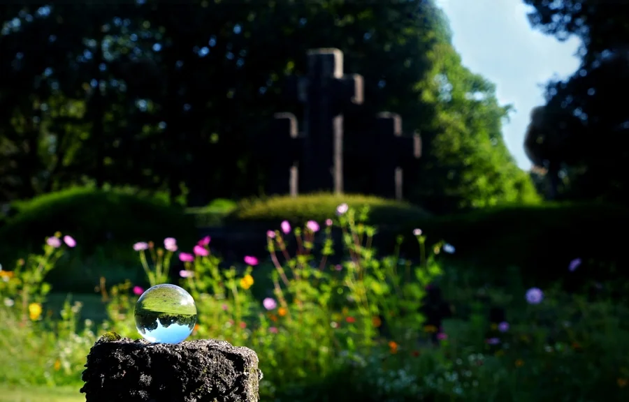 Glaskugel auf einem Stein vor den Kreuzen der Kriegsgräberstätte in Weeze.