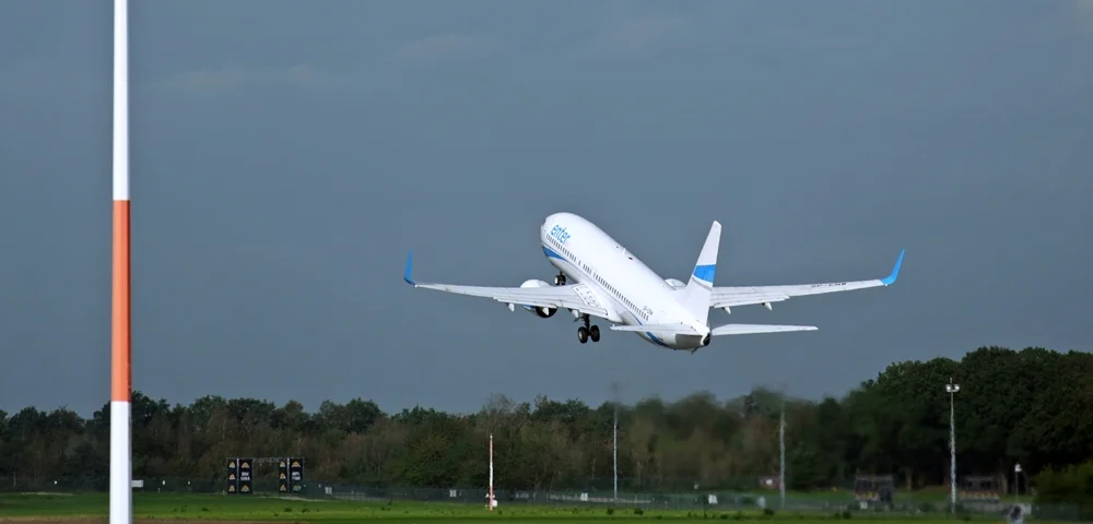 SPassagierflugzeug hebt vom Flughafen Weeze ab und steigt vor dunklen Wolken in den Himmel.