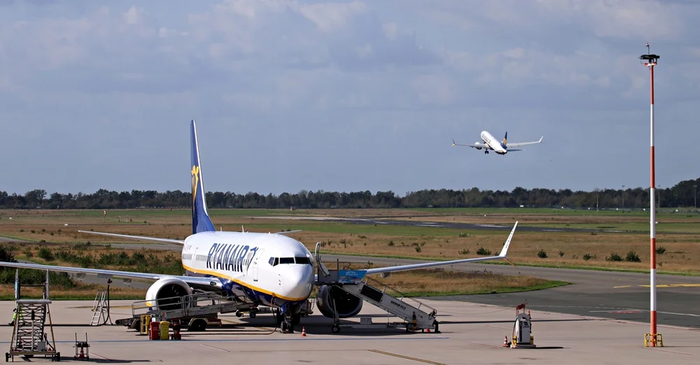 Ryanair-Flugzeug auf dem Vorfeld des Flughafens Weeze, während im Hintergrund eine weitere Maschine startet