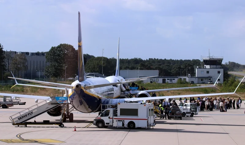 Passagiere warten auf dem Vorfeld des Flughafens Weeze vor zwei Ryanair-Flugzeugen