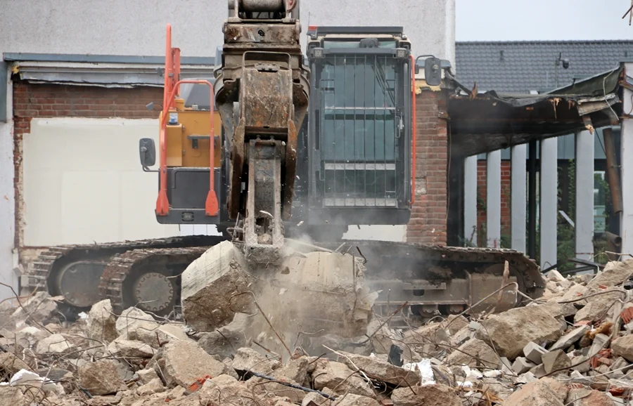 Nahaufnahme eines Volvo-Greifbaggers auf der Abrissbaustelle der Johannes-Hauptschule in Weeze. Die Abbruchzange zerdrückt einen Betonblock zwischen Schutt und Staub.