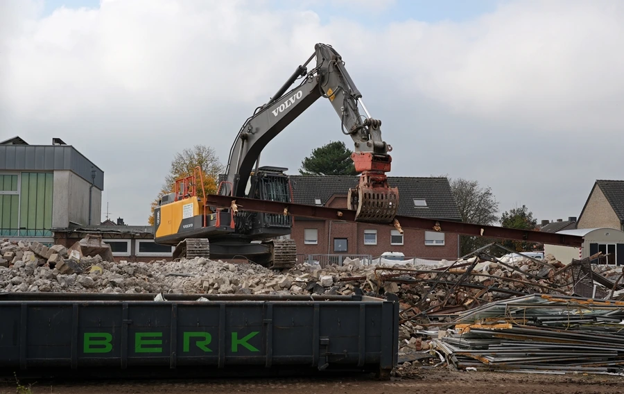 Greifbagger transportiert einen langen Stahlträger auf dem Gelände der ehemaligen Hauptschule Weeze