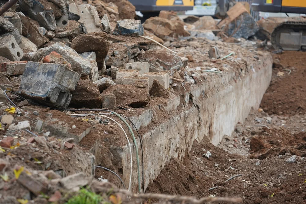 Eine freigelegte Betonkante mit alten Leitungen und Schuttresten erinnert noch an die Fundamente der ehemaligen Schule in Weeze.