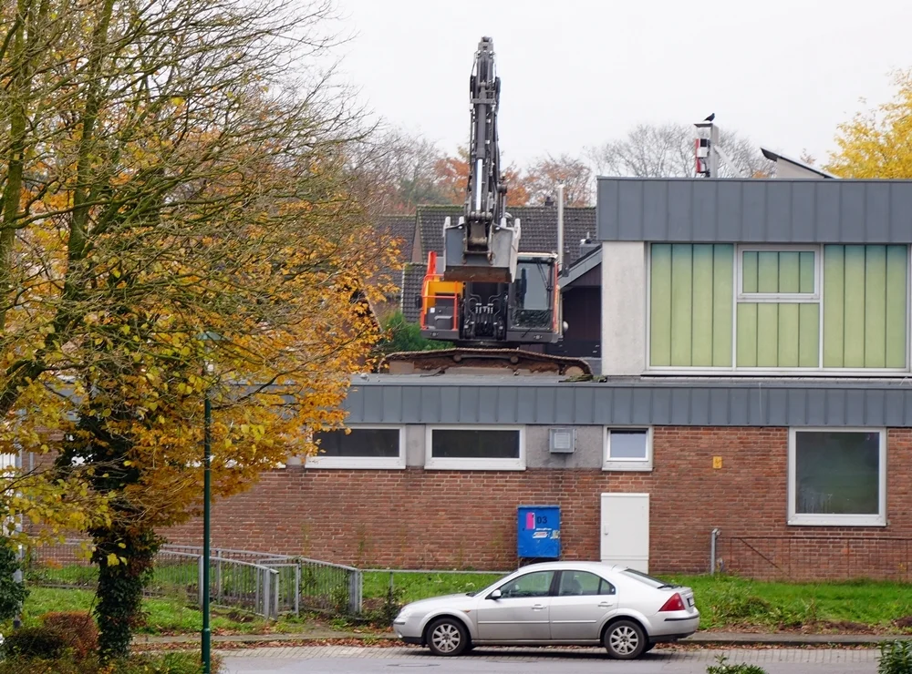 Von dieser Perspektive aus sieht es fast so aus, als würde der Volvo-Bagger auf dem Schuldach stehen –
         tatsächlich arbeitet er hinter dem Gebäude auf einem Schuttberg.