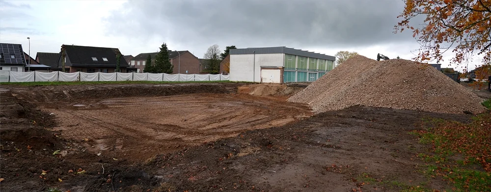 Großer Panoramablick über die Baustelle der neuen Schule in Weeze mit eingeebnetem Gelände, hohem Schotterberg und herbstlichem Himmel.
