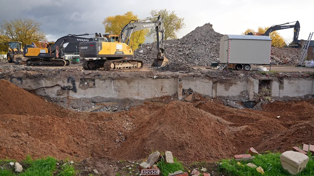 Zwischen freigelegten Fundamenten und hohen Schuttbergen arbeiten mehrere Volvo-Bagger am Abriss der alten Schule in Weeze.