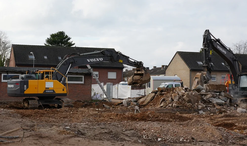 Zwei mächtige Volvo-Bagger arbeiten gleichzeitig am Abbruch der alten Schule und bewegen große Beton- und Steinreste.