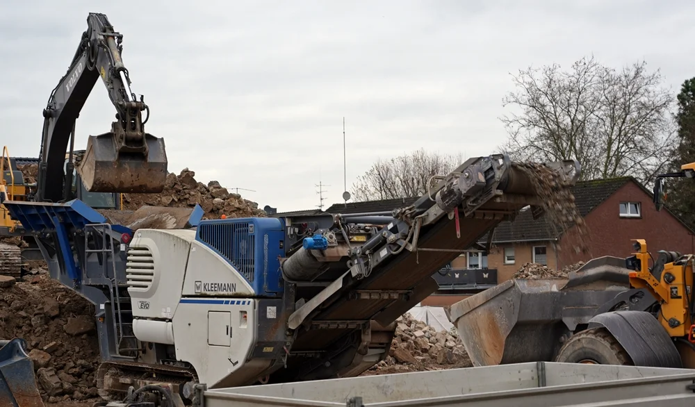 Die mobile Kegelbrechermaschine recycelt den Abbruchschutt der alten Schule in Weeze – Beton und Steine werden direkt weiterverarbeitet.