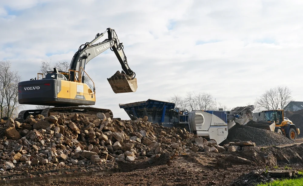 Volvo-Bagger, Kegelbrechermaschine und Radlader arbeiten gemeinsam am Recycling des Abbruchmaterials der alten Schule in Weeze.