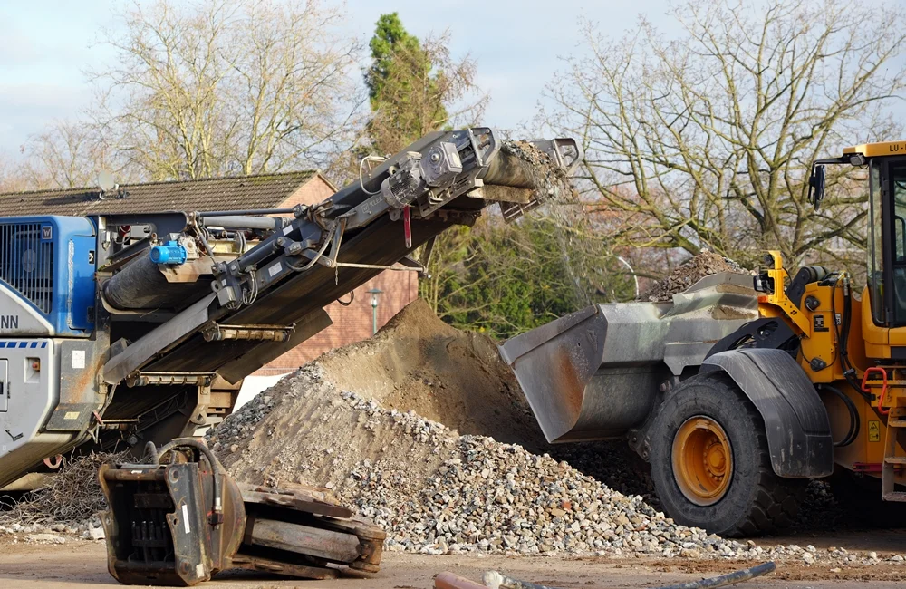 Die mobile Brechanlage recycelt Beton- und Steinreste der alten Schule in Weeze, während der Radlader das neue Material direkt weitertransportiert.