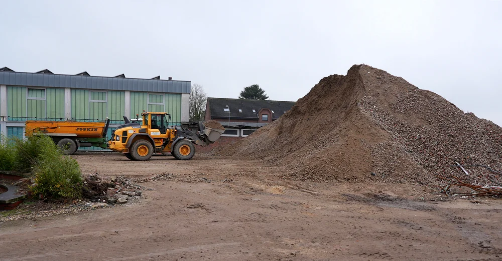 Neben einem riesigen Berg aus Beton- und Steinresten verladen Baumaschinen Recyclingmaterial auf dem Gelände der ehemaligen Johannes-Hauptschule in Weeze.