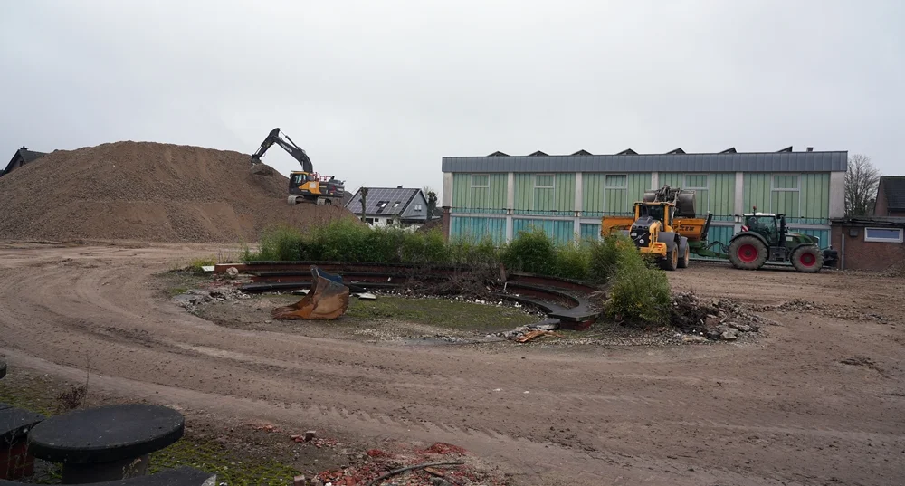 Panoramaaufnahme der Abrissbaustelle in Weeze mit großem Schuttberg, Baggerarbeiten und der alten Turnhalle im Hintergrund.