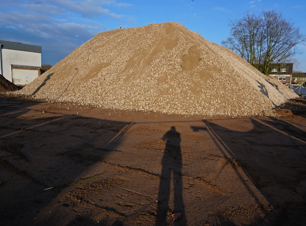 Der riesige Berg aus recyceltem Beton- und Steinmaterial wirkt im warmen Abendlicht fast wie ein kleiner Hügel auf dem ehemaligen Schulgelände in Weeze.