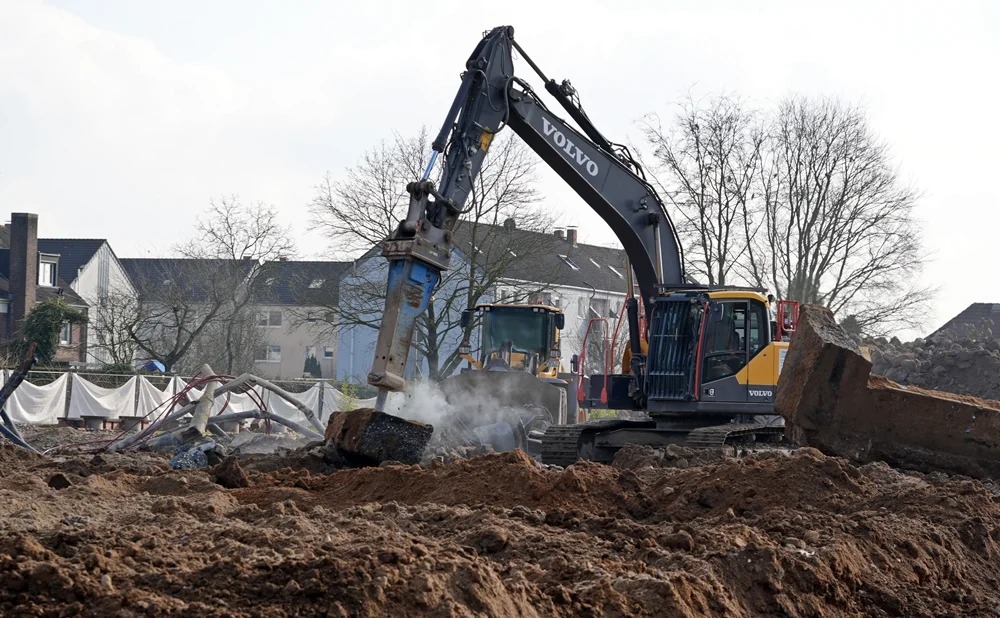 Ein Volvo-Bagger zerkleinert mit schwerem Hydraulikhammer Betonreste auf dem ehemaligen Schulgelände der Johannes-Hauptschule in Weeze.