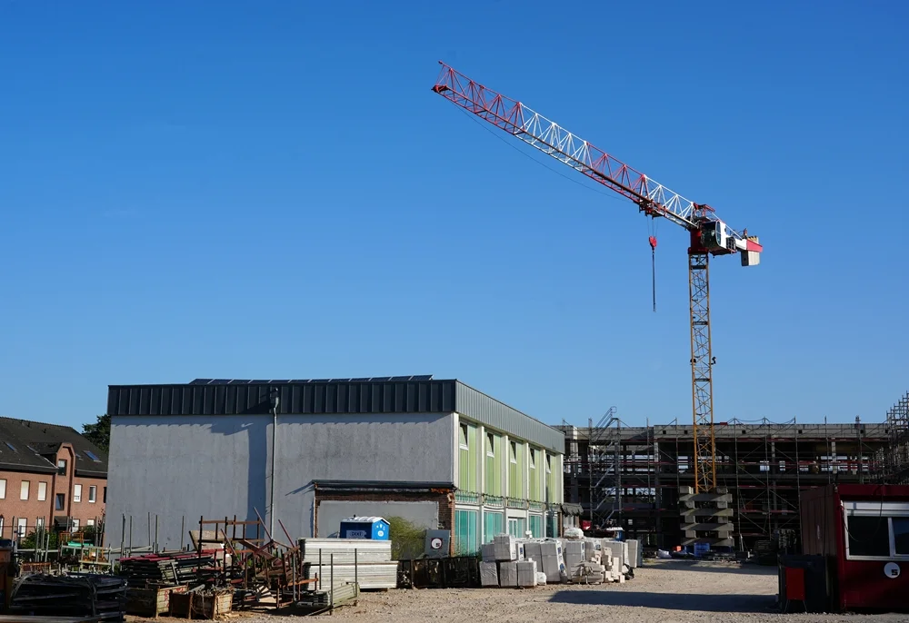 Panoramablick über die Baustelle mit Kran und alter Sprothalle der Hauptschule im Juli 2026.