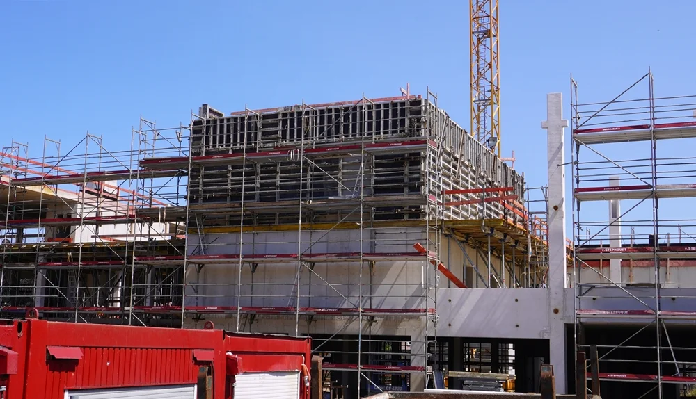 Seitlicher Blick auf den mittleren Gebäudeteil der neuen Petrus-Canisius-Grundschule in Weeze mit Gerüsten, Schalung und den bereits errichteten Betonstützen.