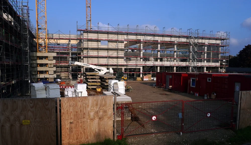 Aktueller Baufortschritt der Petrus-Canisius-Grundschule mit eingerüstetem Neubau und Baustellengelände