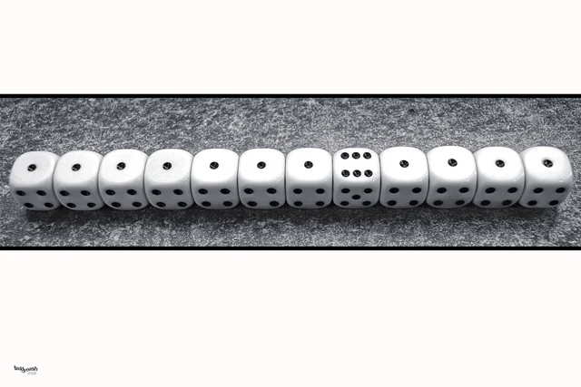 Eine Reihe weißer Spielwürfel liegt nebeneinander auf einer dunklen Oberfläche. Ein einzelner Würfel mit sechs Augen hebt sich als Mittelpunkt der Komposition hervor.