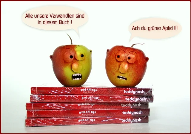 Zwei Äpfel mit Gesichtern stehen auf einem Stapel Bücher und führen ein lustiges Gespräch. Die Szene verbindet Humor, Kreativität und die Welt der Literatur.